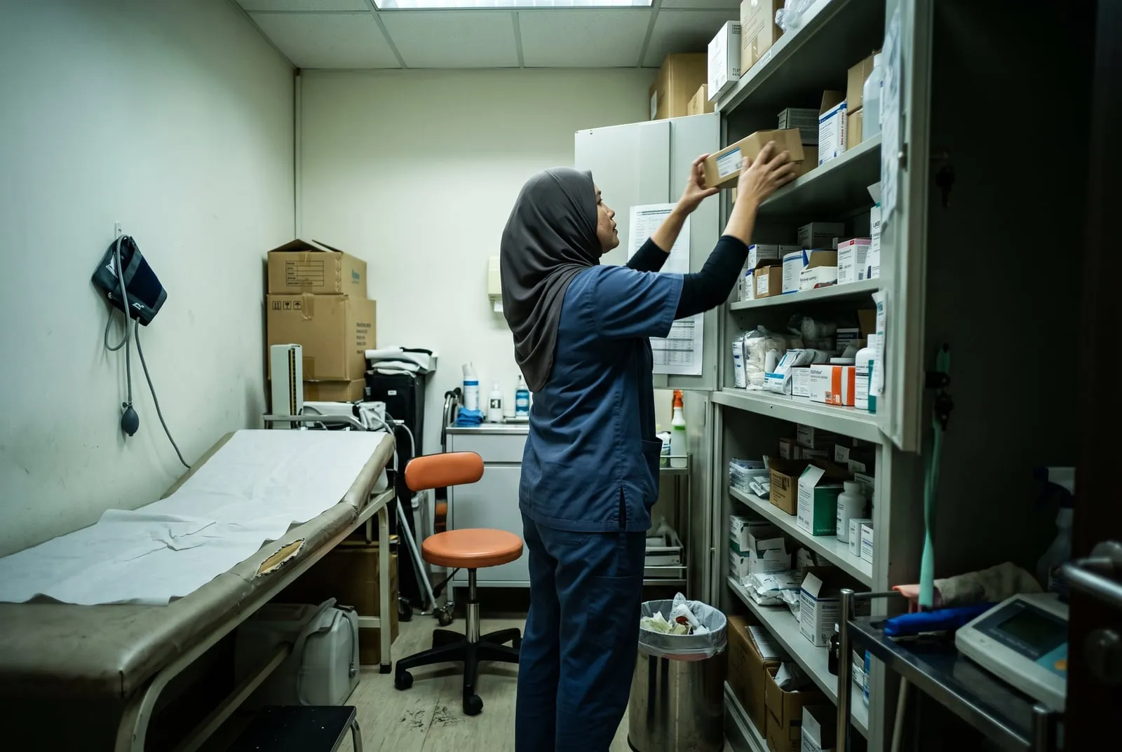 A nurse restocking a treatment room at the end of the day in a Singapore clinic.